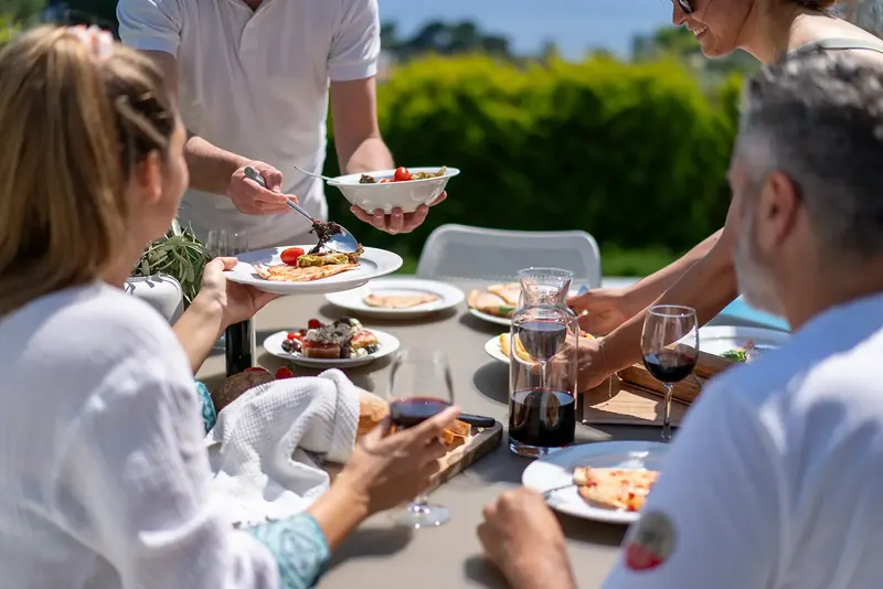 Friends sharing dinner and wine at a table outdoors